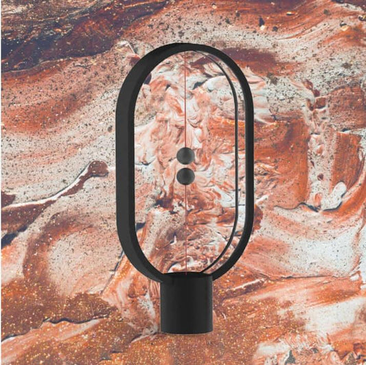 Modern Magnetic Ornament LED lamp in black with oval frame and magnetic pull switch on artistic background.