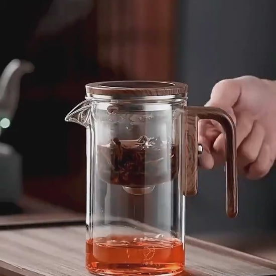 Elegant glass teapot with wooden handle, brewing tea with innovative infuser technology for perfect flavor.